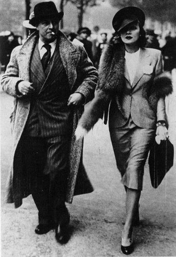 Marlene Dietrich adorned with a silver fox stole walking alongside her husband, Rudolf Sieber, 1930s.