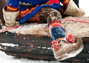 Boy dressed up in traditonal White reindeer fur for Jokkmokk's winter fair, Finland.